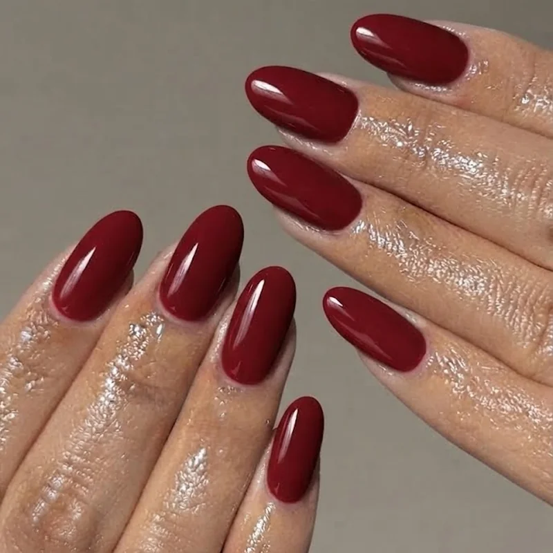 Short to medium oval nails in classic red polish showing a durable low-maintenance everyday manicure
