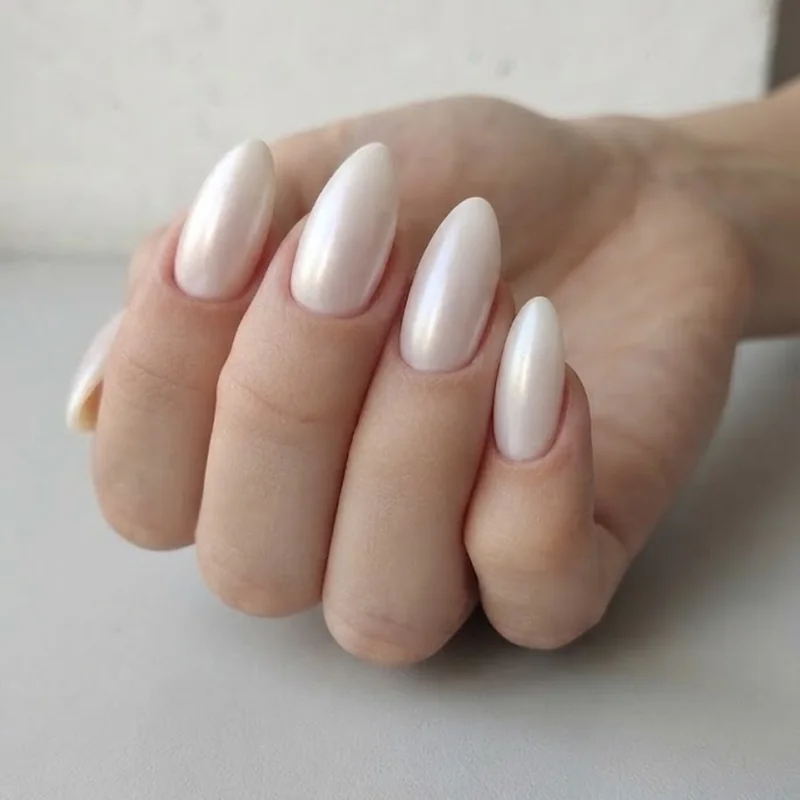 Milky white pearl nail manicure on almond shape nails, photographed up close in soft natural daylight
