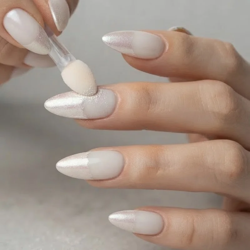 Pearl nail powder chrome finish being applied on a DIY at-home manicure using a silicone applicator tool