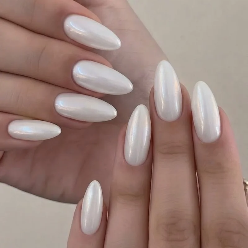 Close-up of pearl nails showing the soft milky iridescent glow on a white gel manicure base in natural daylight