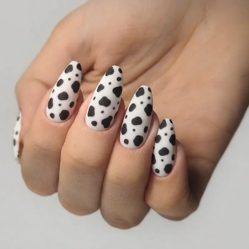 Full coverage matte cow print manicure on coffin nail shape with varied spot sizes