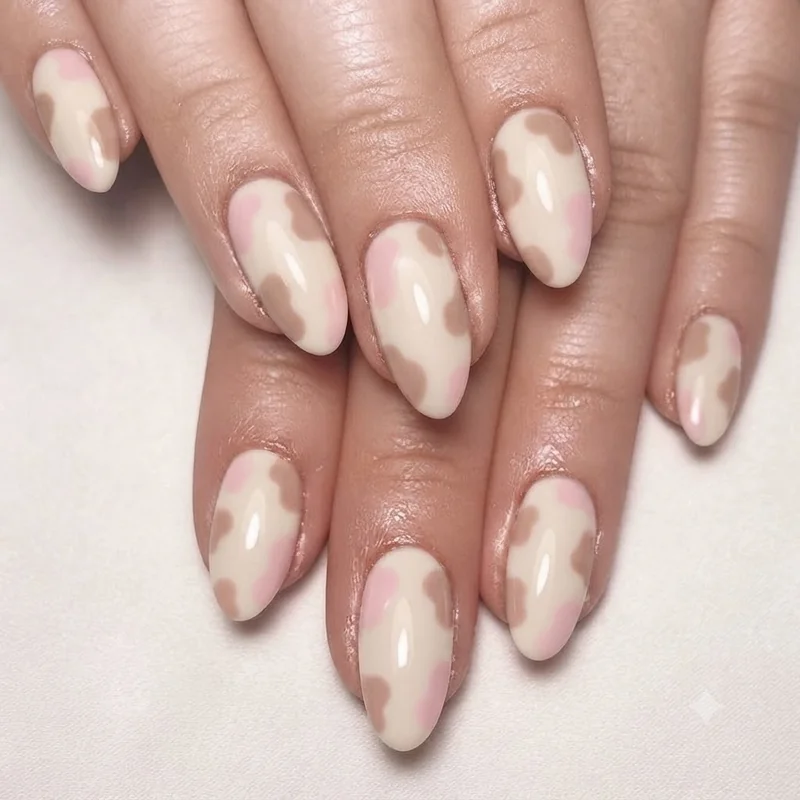 Pink and brown pastel cow print nail manicure on cream base with soft spot placement