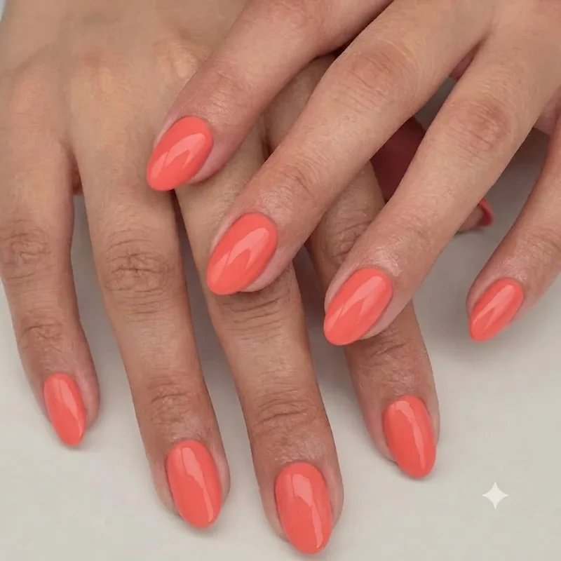 Bright coral summer manicure on almond nails still wearable in early September before the seasonal colour shift begins