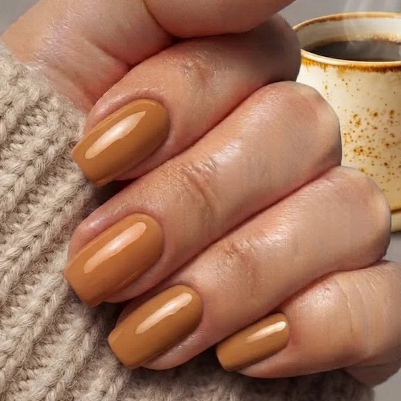 Hands in a cozy fall sweater holding a coffee cup, showing a versatile nail shape that wears well through the entire season