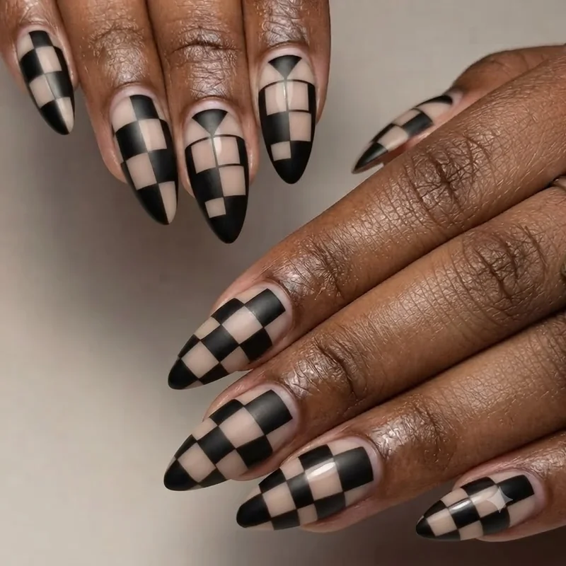 Checkerboard negative space nail design with black and nude squares in a tuxedo-style grid pattern