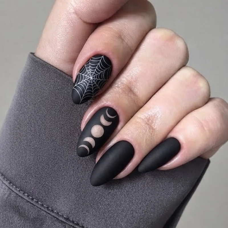 Occult gothic stiletto nails with spiderweb and moon phase negative space detailing on a matte black base