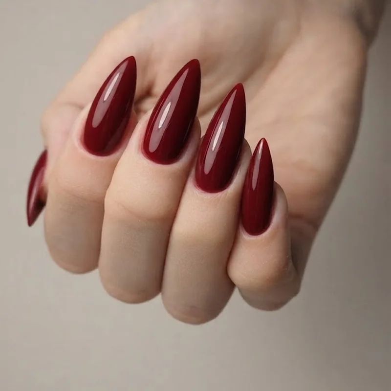 Glossy oxblood and crimson gothic stiletto nails with a dark vampiric red manicure mood
