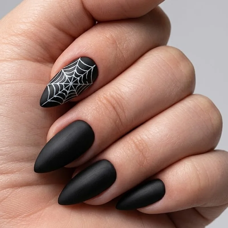 Matte black stiletto nails with a single spiderweb accent nail in gothic styling