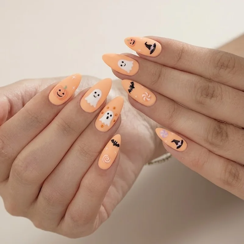 Pastel orange stiletto nails with playful pumpkin and ghost motif, not gory Halloween design