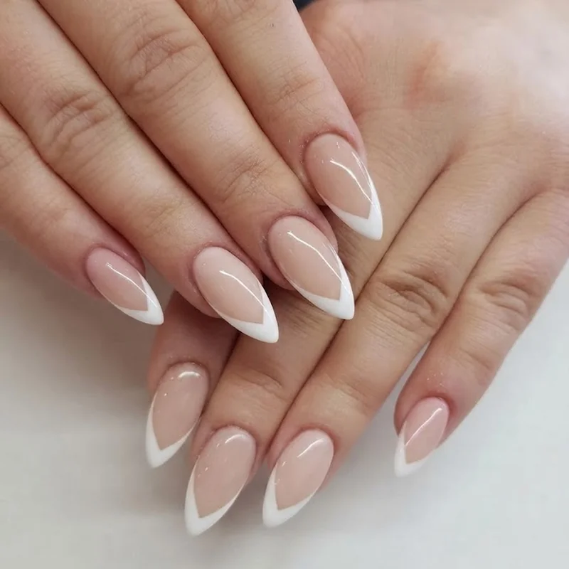 Sharp V-cut white french tip on sheer nude base, stiletto nail shape close-up