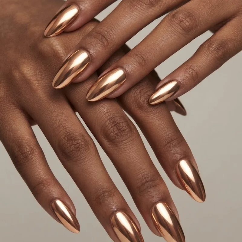 Copper gold chrome stiletto nails catching light with reflective mirror finish on deep skin tone hands