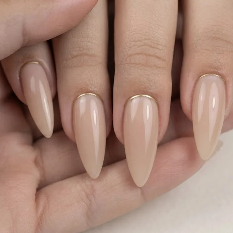 Classy stiletto wedding nails in a champagne nude tone with fine gold cuticle line detail