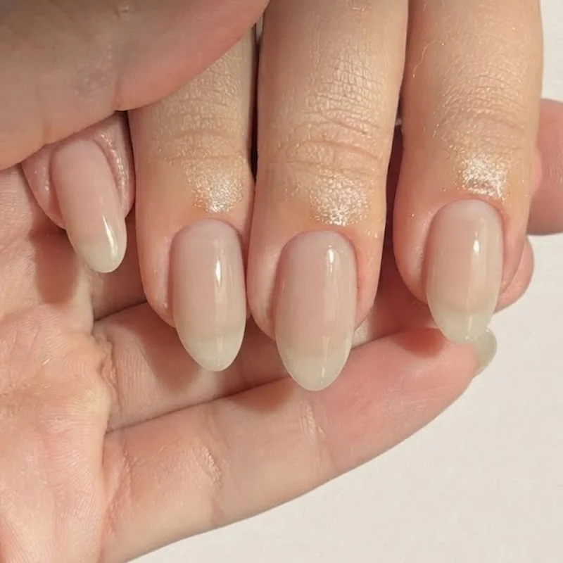 Short almond shaped manicure showcasing an engagement ring with hand posed naturally for a ring selfie photo