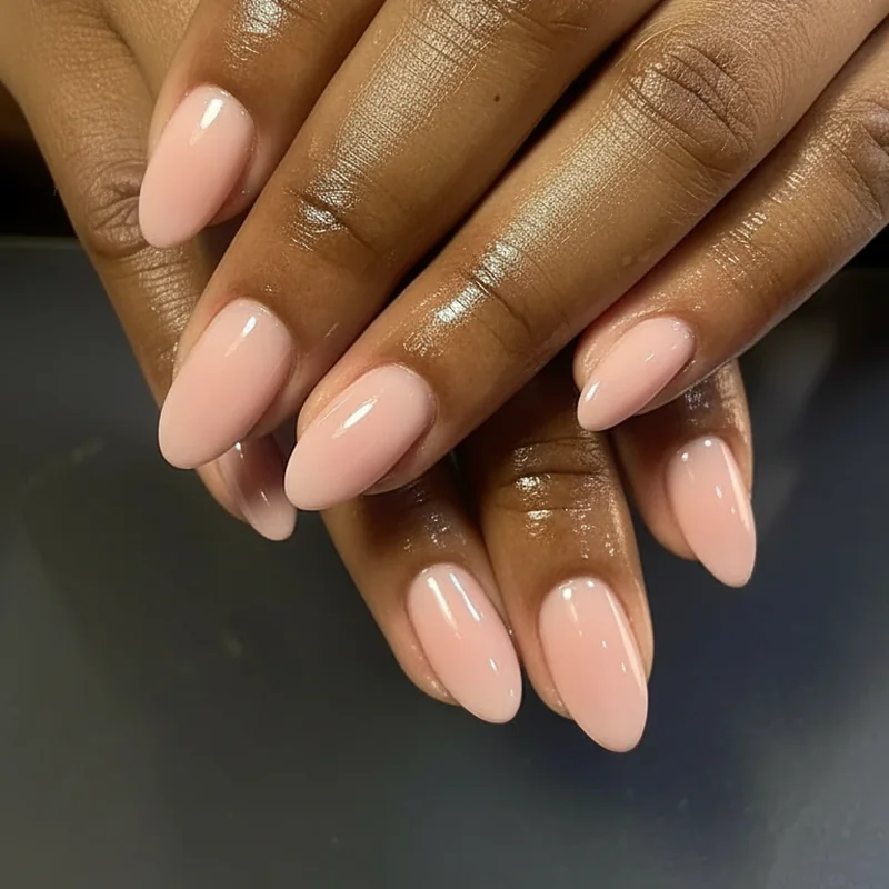 Gel top coat capping the free edge on oval nail tips with sheer pink polish showing a high-shine long-lasting bridal finish