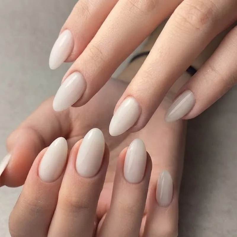 White nails wedding guest manicure in a milky white finish styled on hand against a neutral elegant editorial background