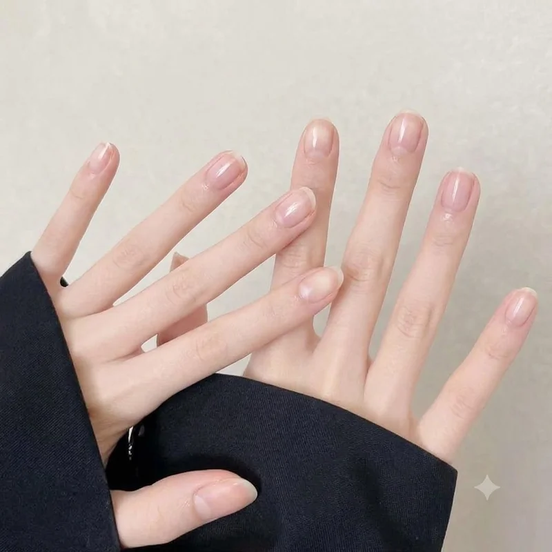 Short natural oval nails with a soft healthy sheen against a chunky knit cuff, showing how winter nails look when hydrated