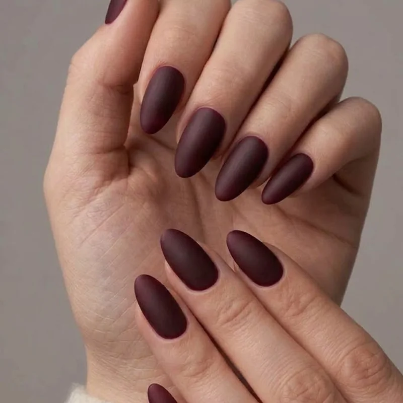 Deep matte burgundy winter nails styled with a cream sweater for cozy contrast