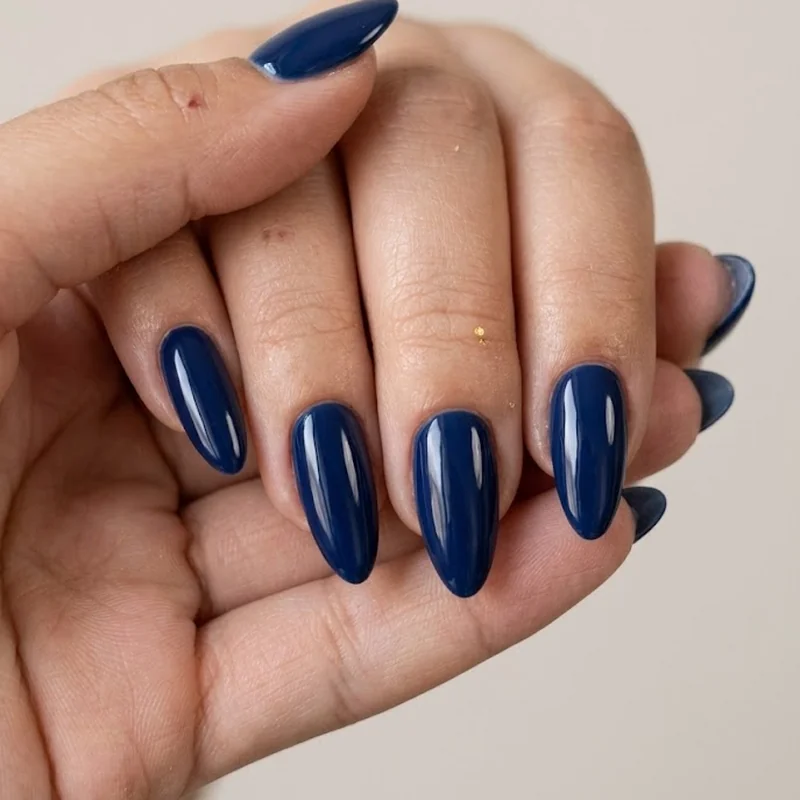 Solid navy blue nail polish on medium-length almond nails with a high-gloss finish