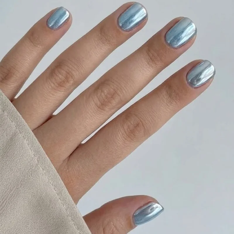 Short winter nails in icy blue and silver chrome polish, showing a mirror-like cool-toned metallic winter finish
