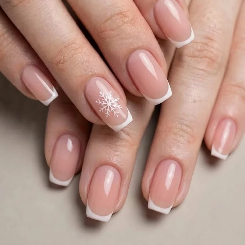 Short winter nails featuring a subtle snowflake accent nail and a French tip variation for festive winter styling