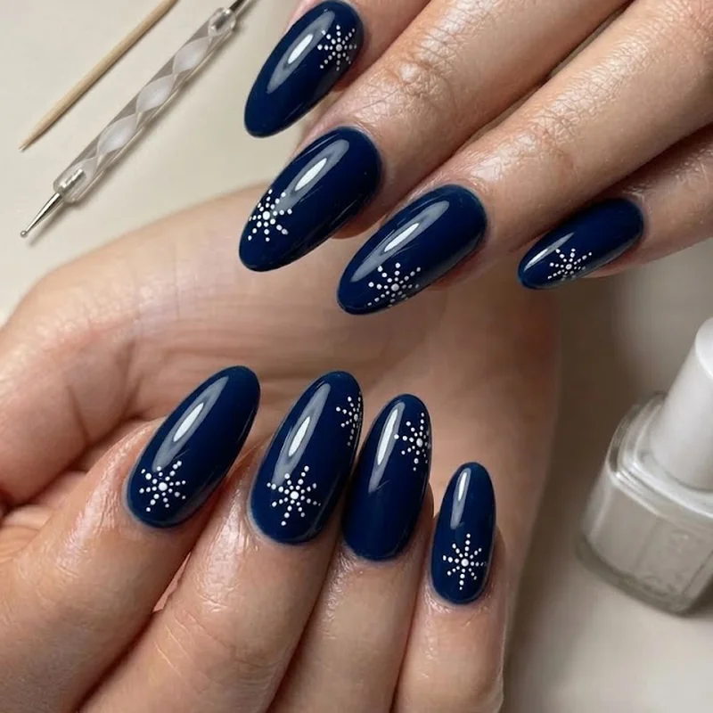 Toothpick and dotting tool laid beside white polish for snowflake nail art supplies