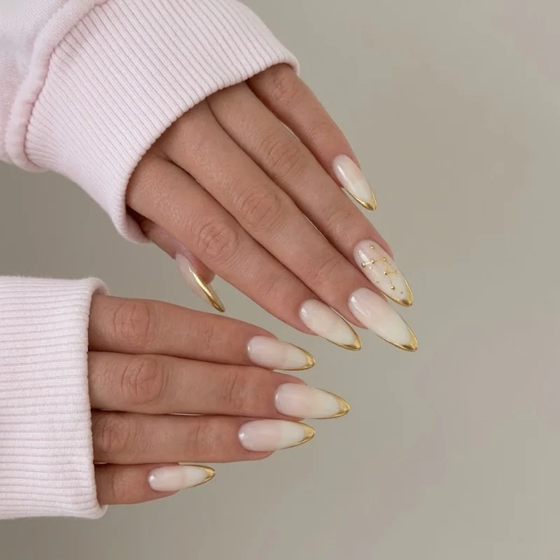 Gold French tip manicure with celestial star design for winter holiday events