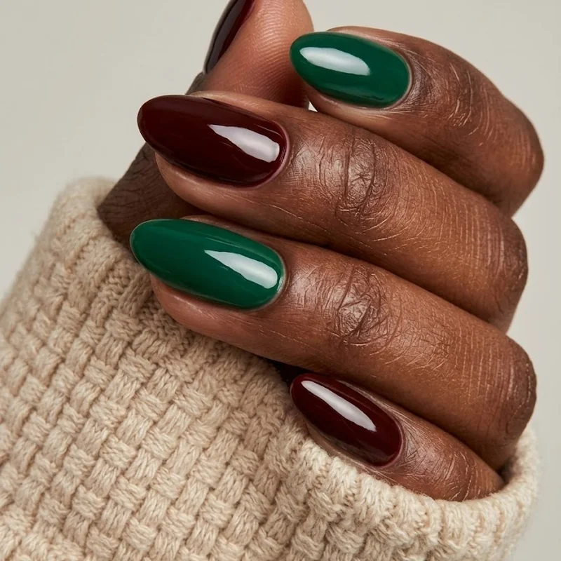 Close-up glossy emerald and oxblood winter nail colors for dark skin on melanin-rich hands