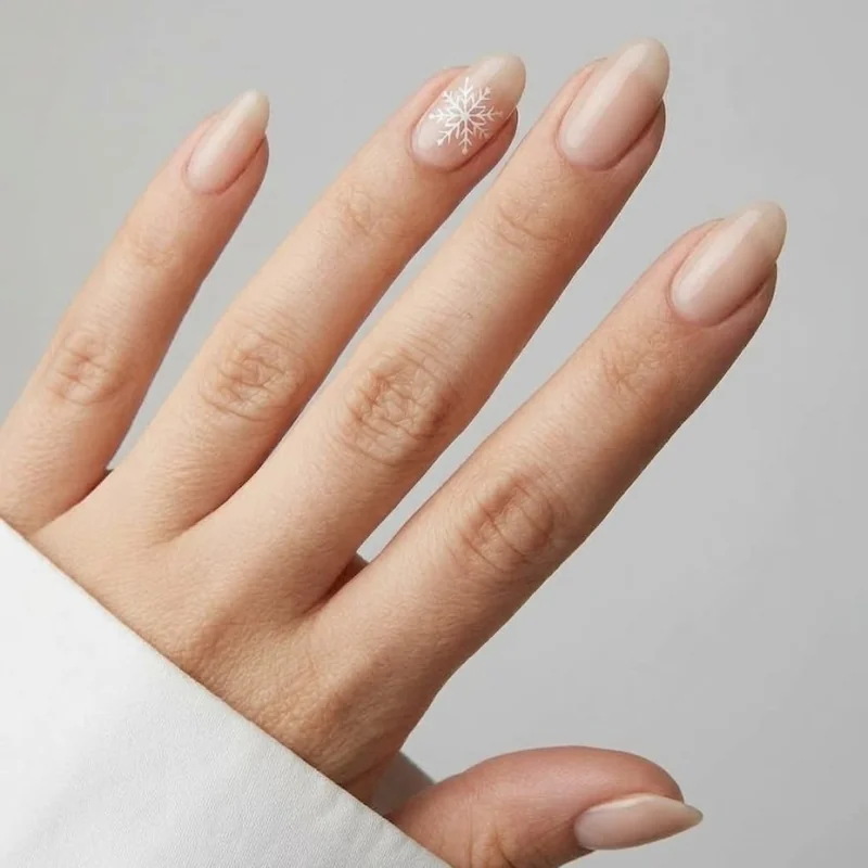 Subtle white snowflake accent nail winter wedding nails on neutral bridal base