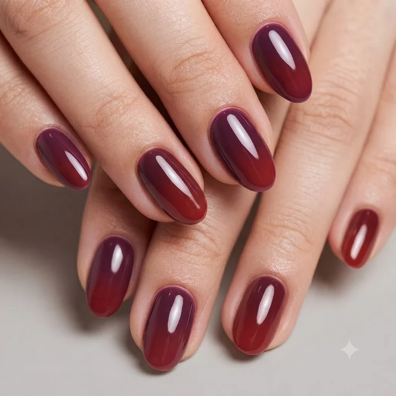 Nail artist layering red and plum polish blend during custom press-on application process
