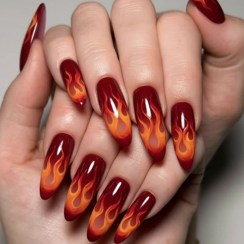 Flame nail art on coffin nails with deep oxblood base and graduated amber orange fire tips for bold Sagittarius fire sign birthday set