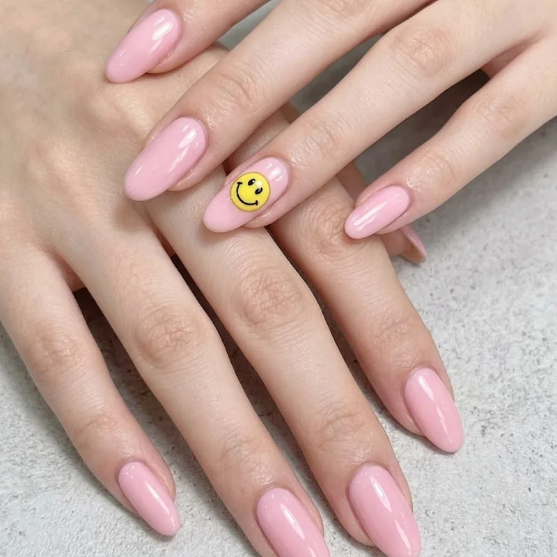 Pastel pink Y2K nails with a hand-painted yellow smiley face accent nail
