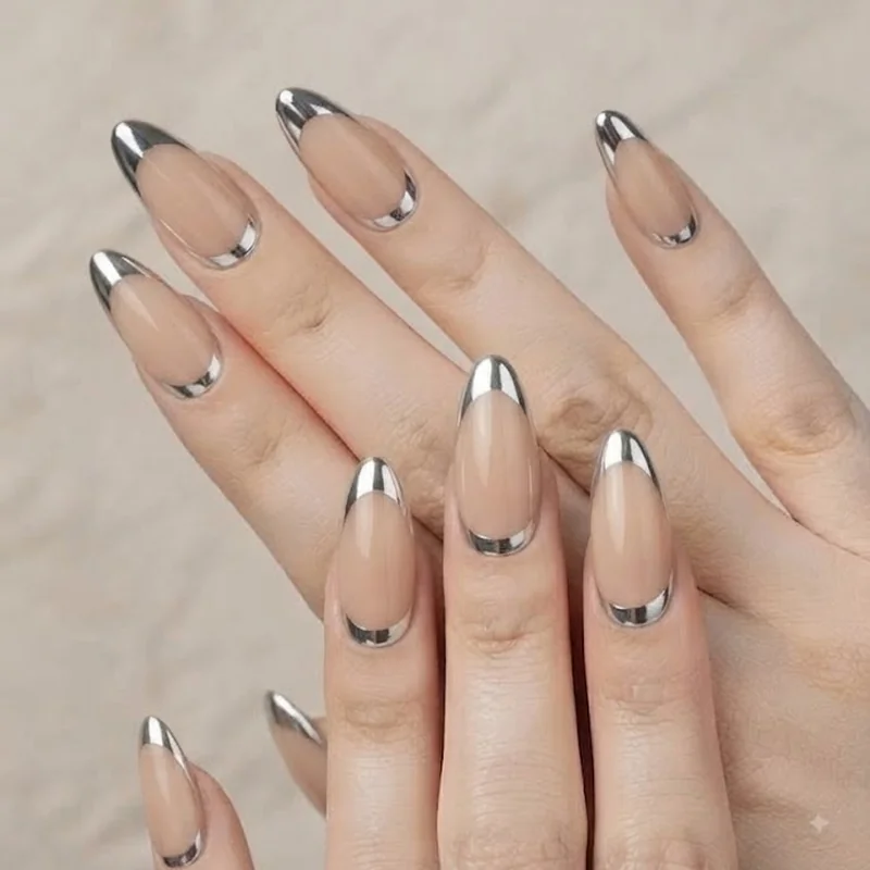 Silver mirror chrome French tip nails over a nude base on almond shape