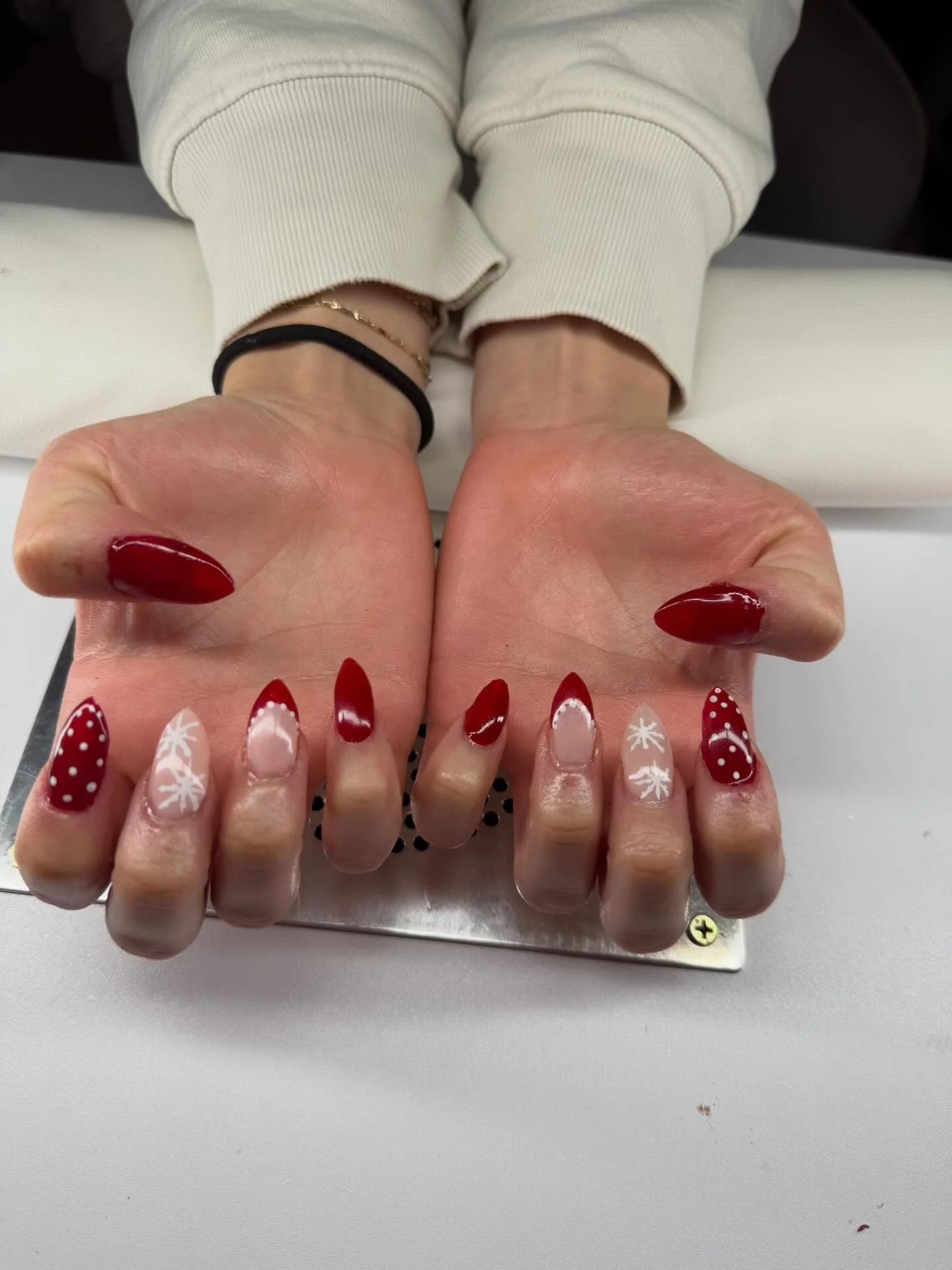 Red gel almond nails with hand painted snowflake holiday nail art by Peyton Combs Michigan nail artist Shelby Township