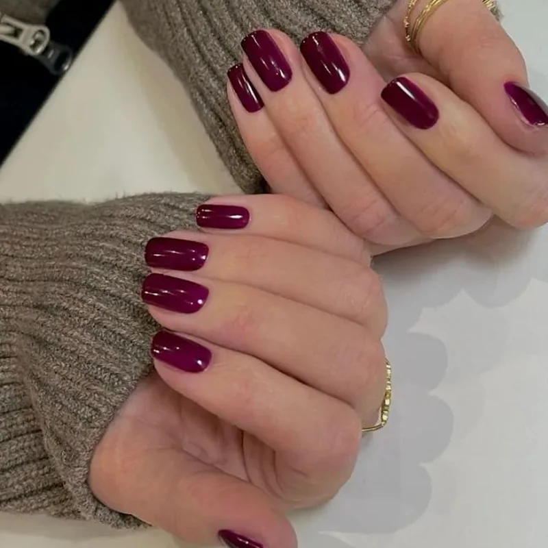 Fair cool undertone hands with burgundy wine berry colored manicure showing sophisticated depth
