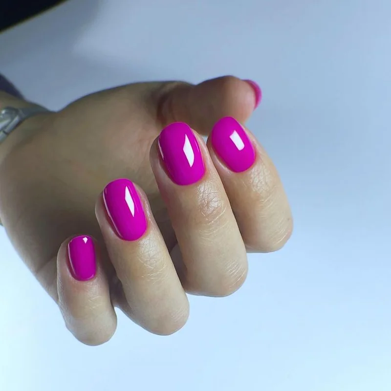 Medium cool undertone hands with fuchsia magenta vibrant nail polish creating bold fashion statement
