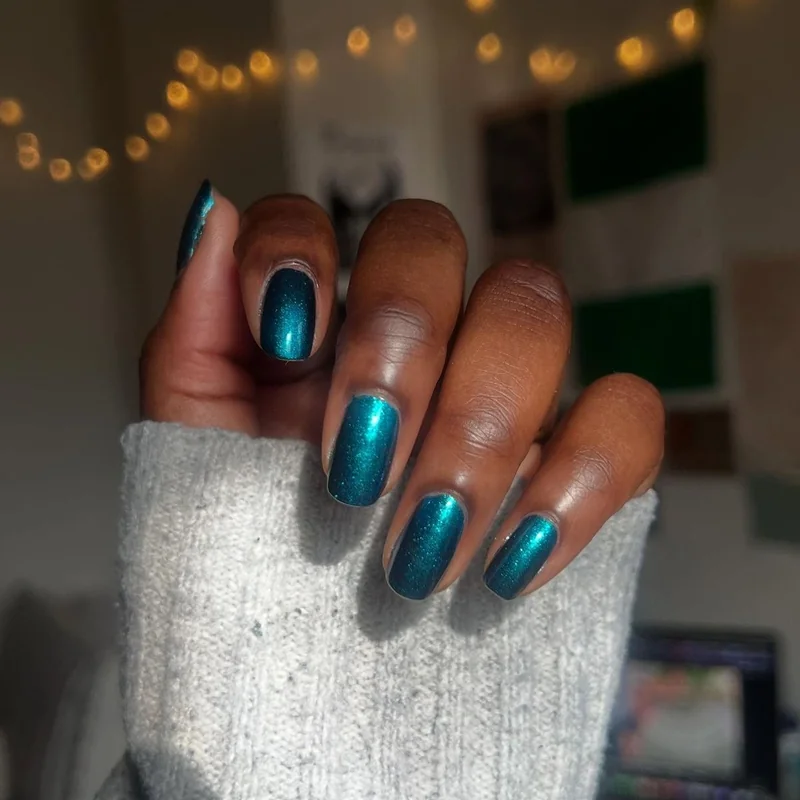 Medium cool skin tone displaying deep teal peacock blue nail polish sophisticated unique color choice