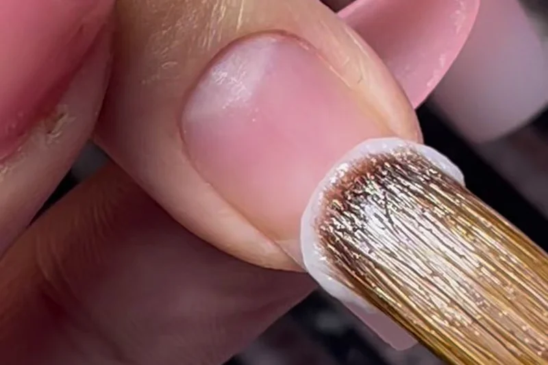 Sealing nail free edge with polish brush horizontally across tip to prevent chipping and extend manicure wear time