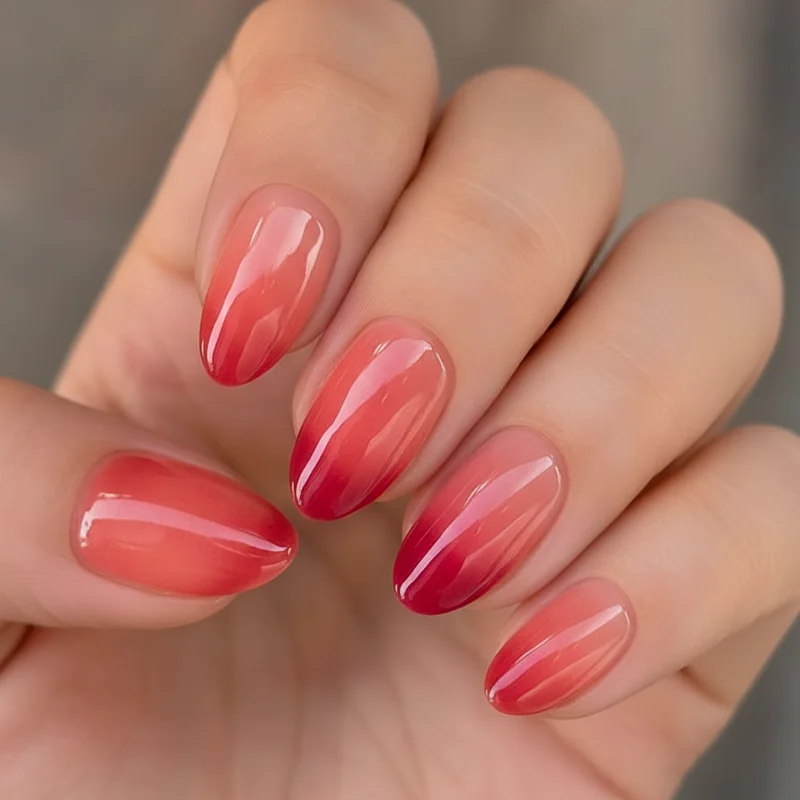 Jelly nails summer 2026 trend translucent coral and cherry shades with glossy glazed finish on short almond shape dimensional sheer effect