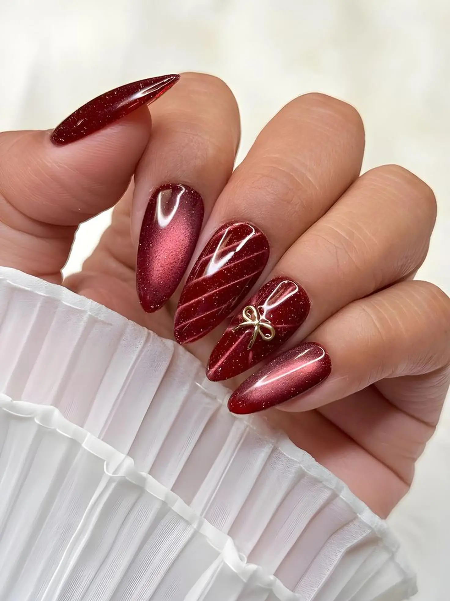Burgundy velvet cat eye nails with magnetic dimensional finish creating trendy winter manicure with light catching wine red effect