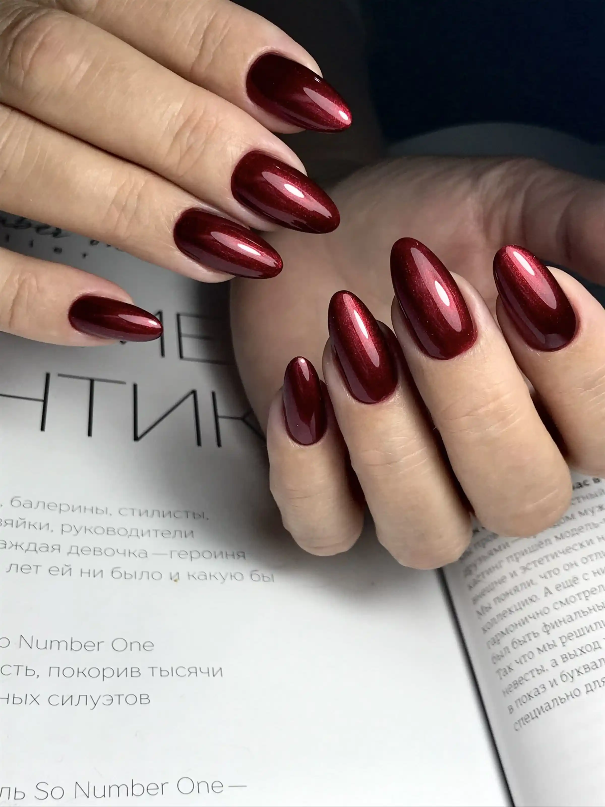 Cherry wine glossy almond nails with shiny burgundy finish creating elegant trendy winter manicure perfect for romantic occasions