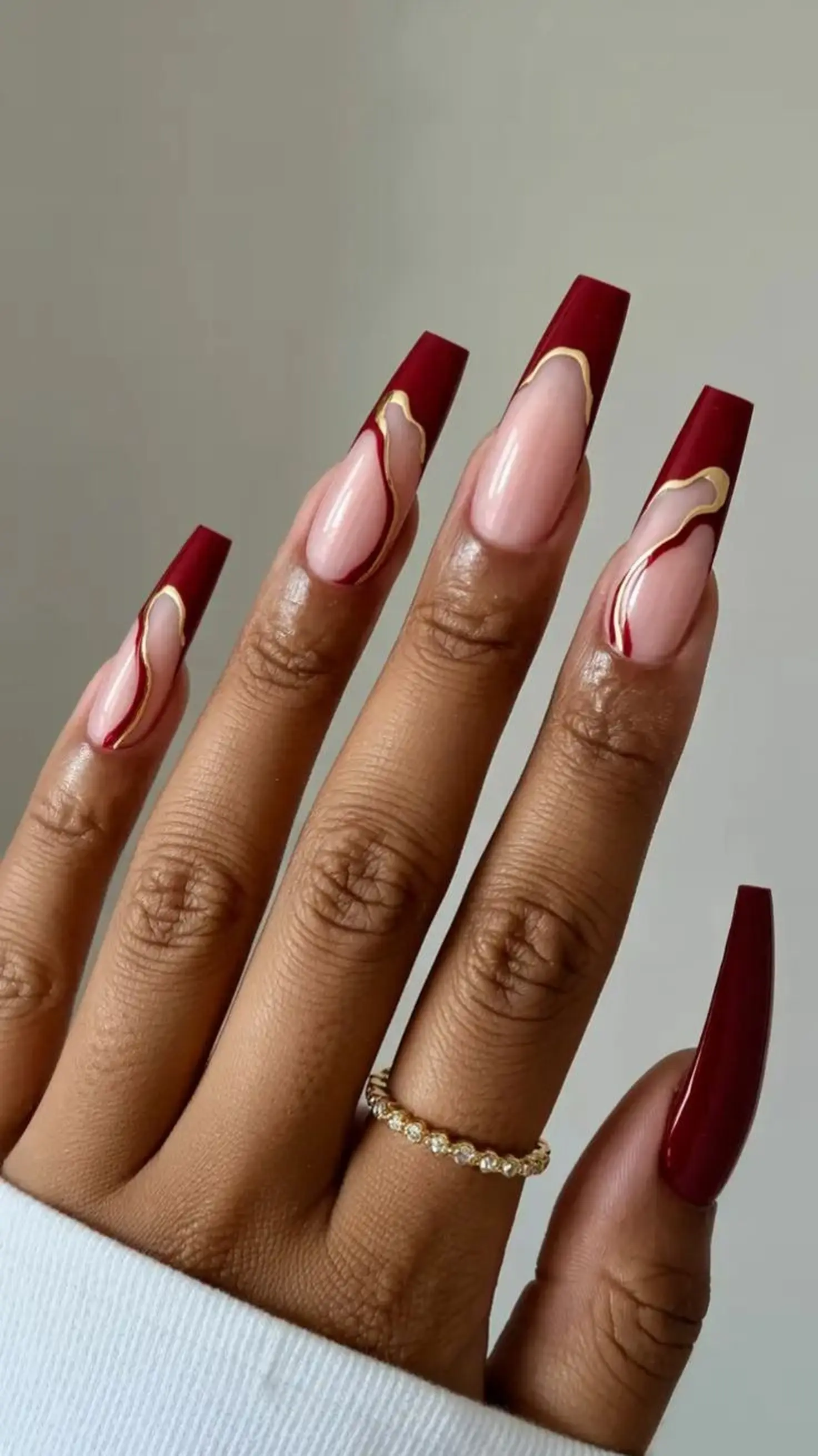 Dark red burgundy coffin nails with dramatic finish creating bold statement winter party manicure perfect for holiday celebrations