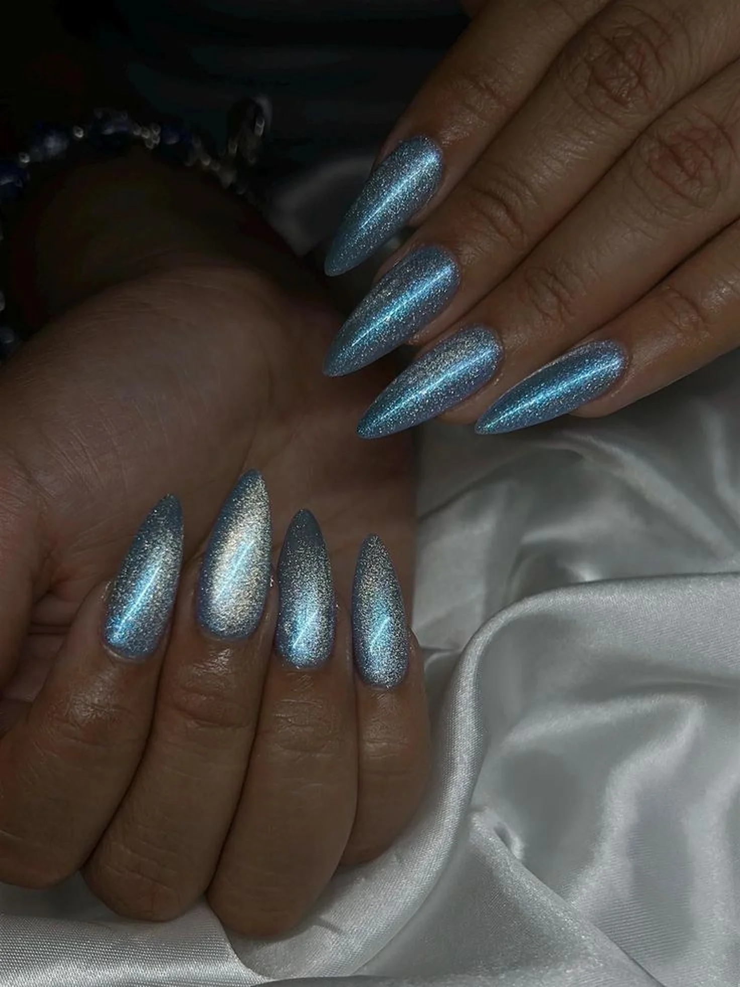 Blue chrome cat eye nails with magnetic metallic finish creating dimensional winter party manicure with light catching stripe effect