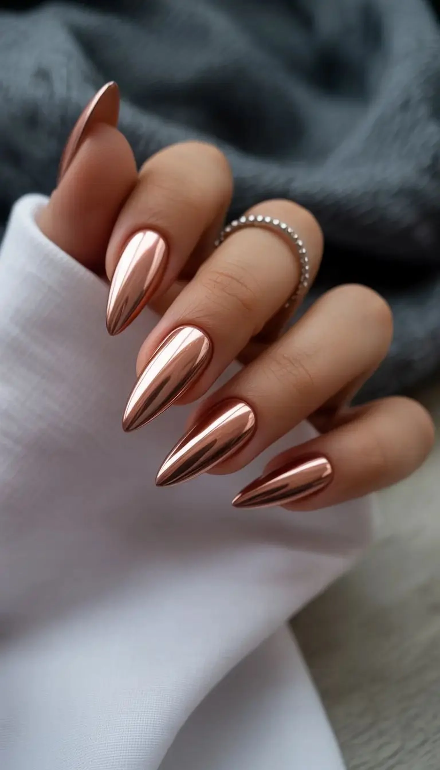 Copper chrome almond shape nails with warm bronze metallic finish creating trendy winter manicure perfect for neutral fashion lovers