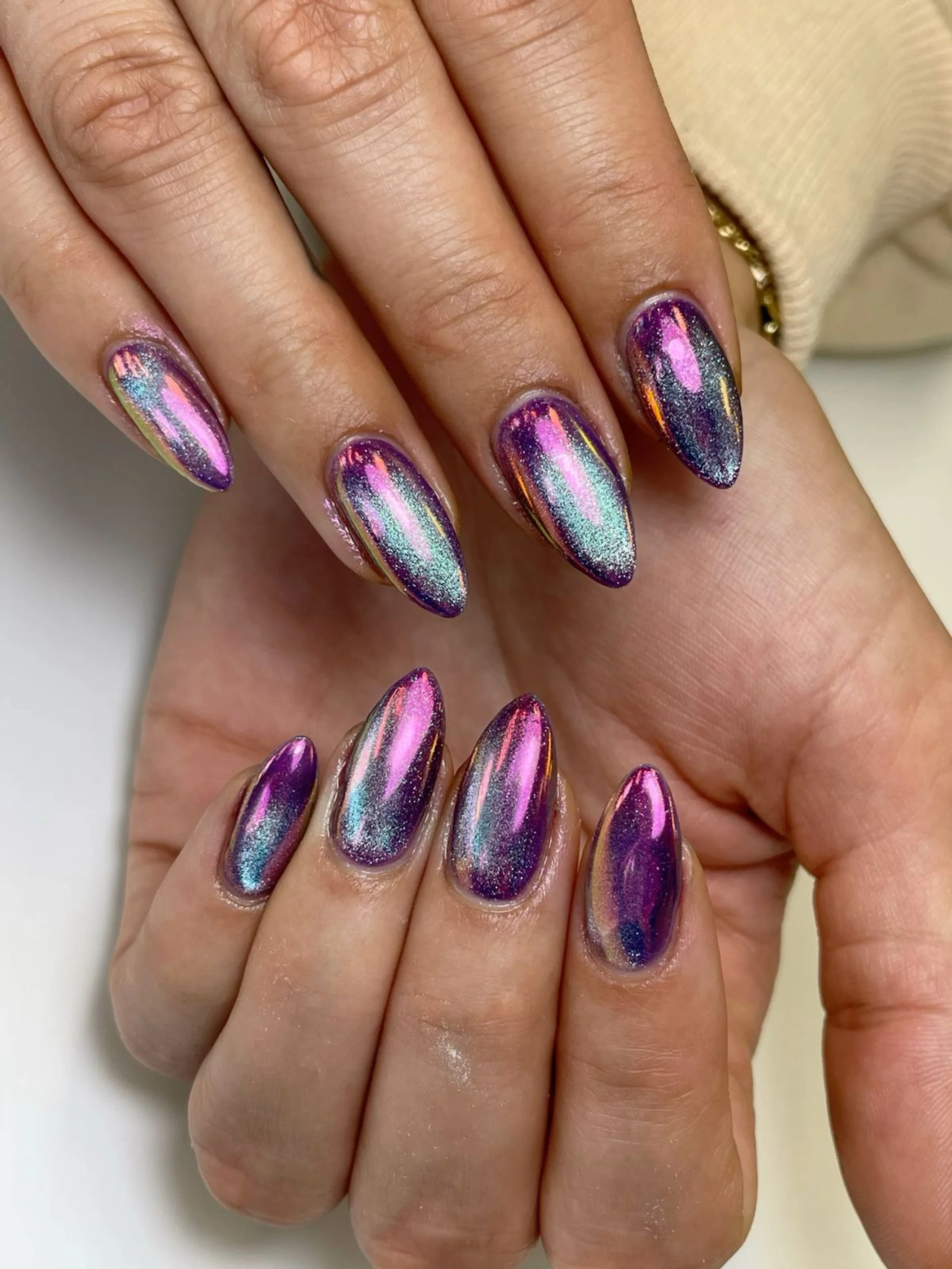 Oil slick chrome almond nails with multi-color shift effect creating rainbow metallic winter nail art trending design 2025