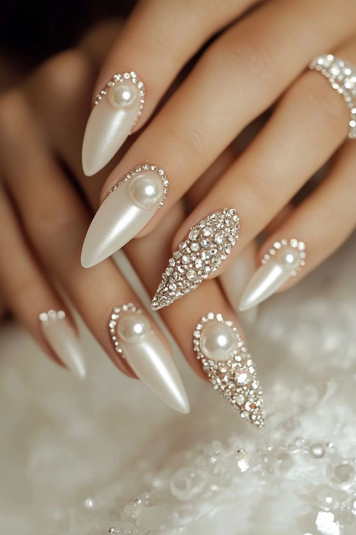 Pearl white chrome nails with 3D gem accents creating luxury winter wedding manicure with soft metallic shine and rhinestone details