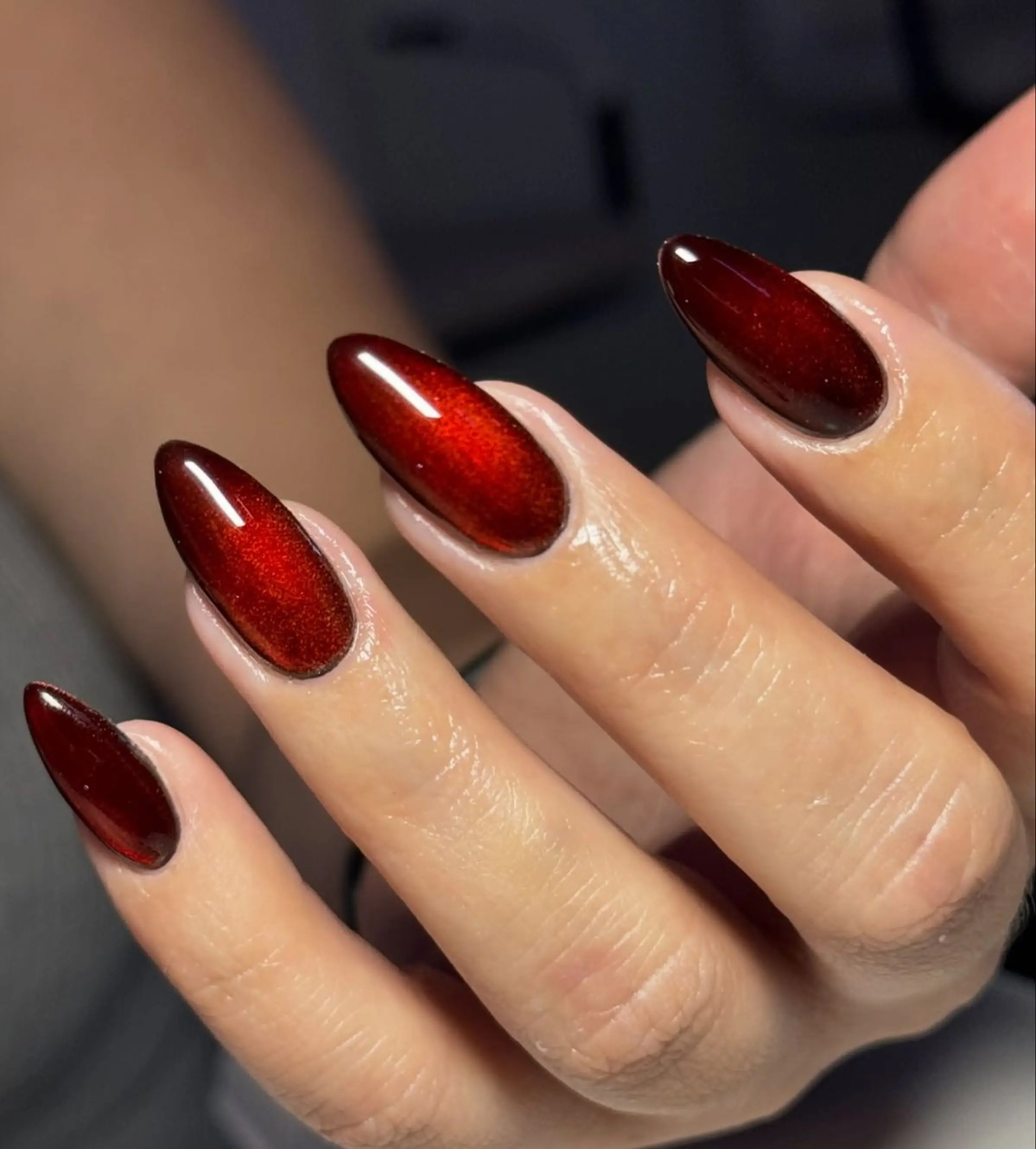 Ruby velvet glossy almond nails with cat eye magnetic creating luxe red winter manicure finish perfect for elegant party events